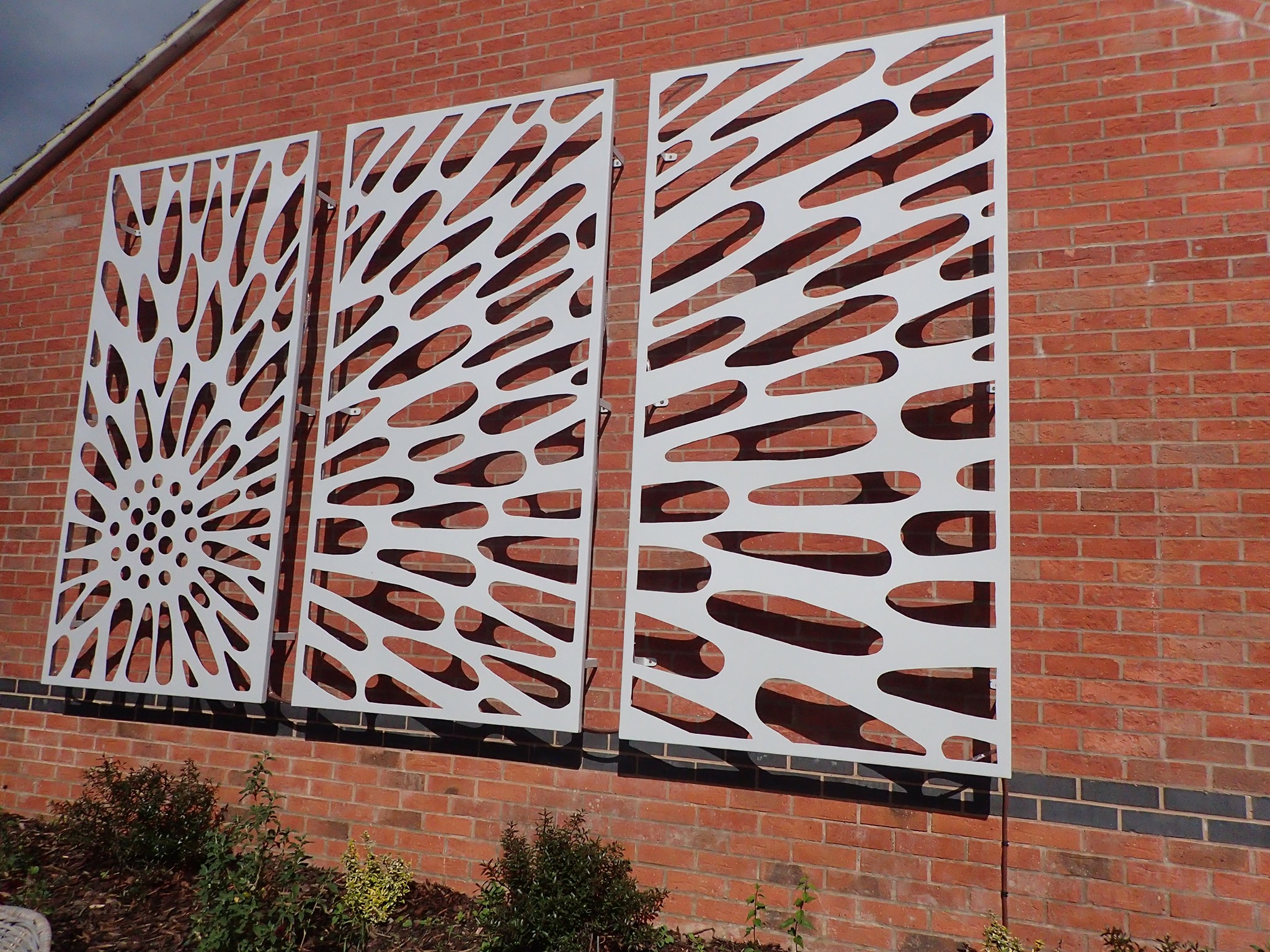 Metal powder-coated sculpture attached to a wall.