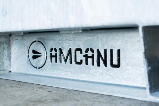 Amcanu logo cut out of metal in enclosure